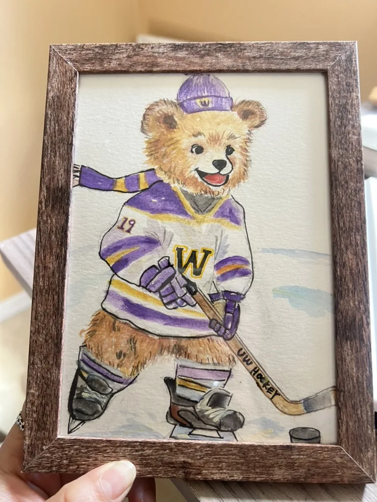 Watercolor of a teddy bear in a purple and gold UW hockey jersey